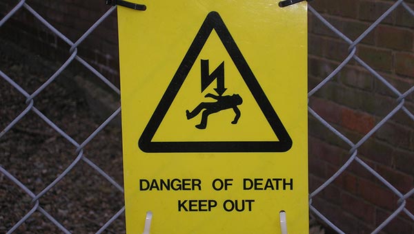 Sign showing a horizontal body with a lightning-like arrow pointing at it, reading "Danger of Death: Keep Out"