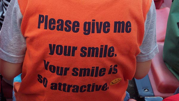 Child's t-shirt reads "Please give me your smile. Your smile is so attractive."